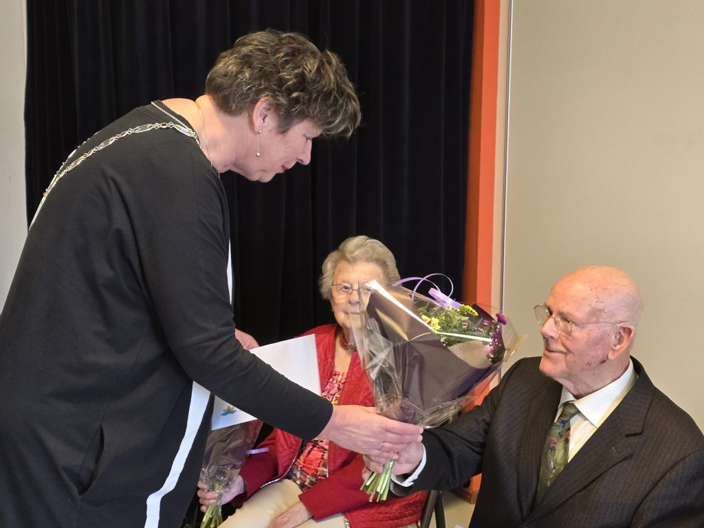 burgemeester reikt bos bloemen uit aan inwoner Hollands Kroon