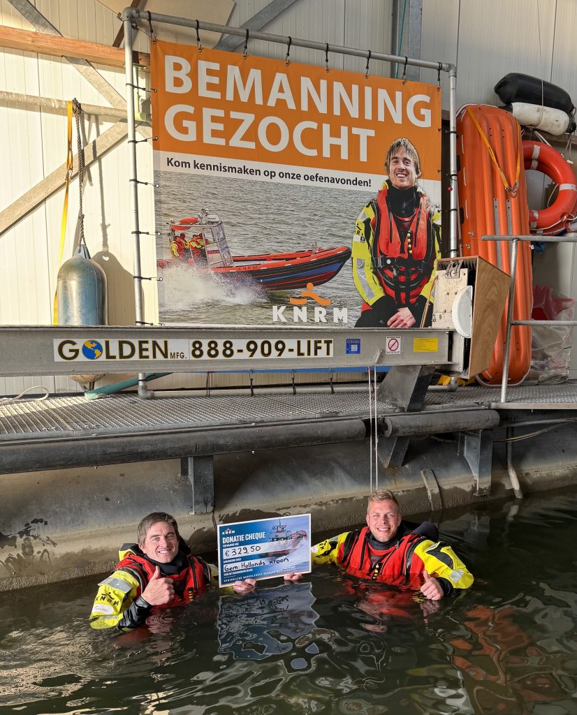 Schipper Eduard Terpstra (KNRM) stond in een droogpak in het water en ontving de cheque van Stefan Tijsen van het Ondernemersloket.