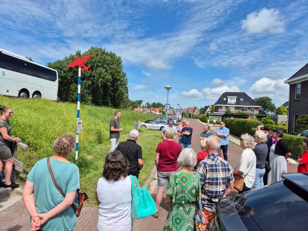 Bestuurslid van Stichting Herdenkingspalen geeft uitleg aan raadsleden en het college over de herdenkingspaal.