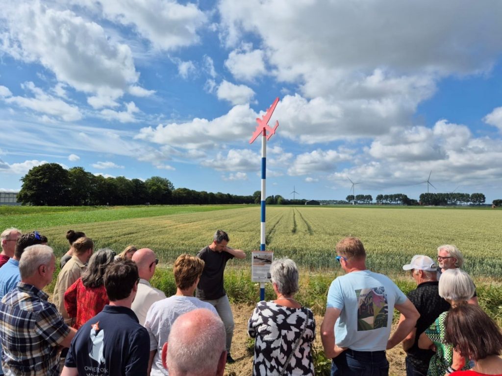 Groep mensen bij een herdenkingspaal in Hollands Kroon.