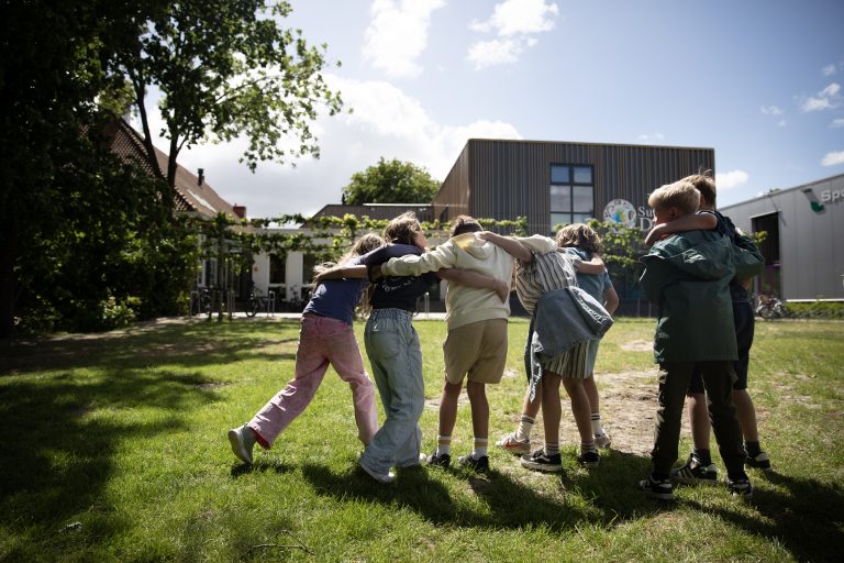 Jongeren in een rondje buiten arm in arm