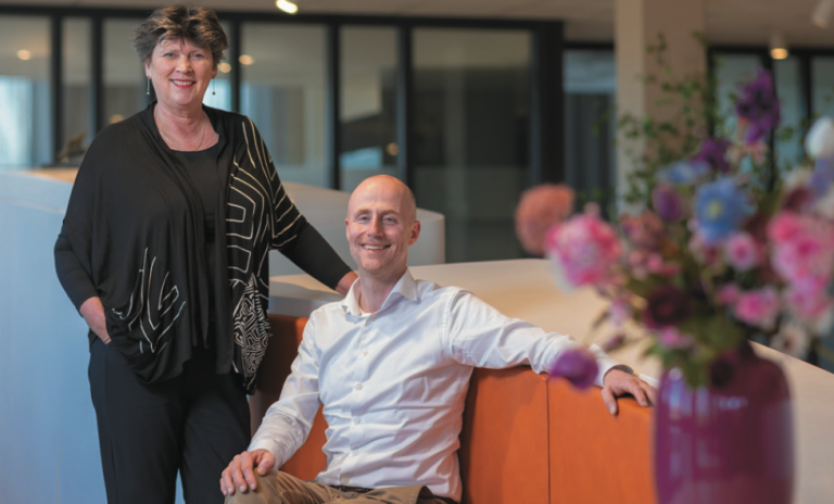 Foto van burgemeester Rian van Dam (staand) naast wethouder Robert Leever (zittend)