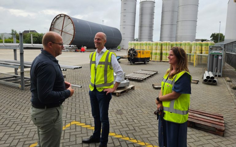 Wethouder Robert Leever op bezoek bij Oostwouder Tank- & Silobouwer BV. Ze staan met elkaar op het bedrijventerrein en zijn in gesprek. IO de achtergrond een grote sili