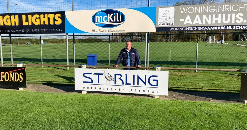 Mike Bijvoet bij het bord van Starling Workwear bij voetbalvereniging Winkel