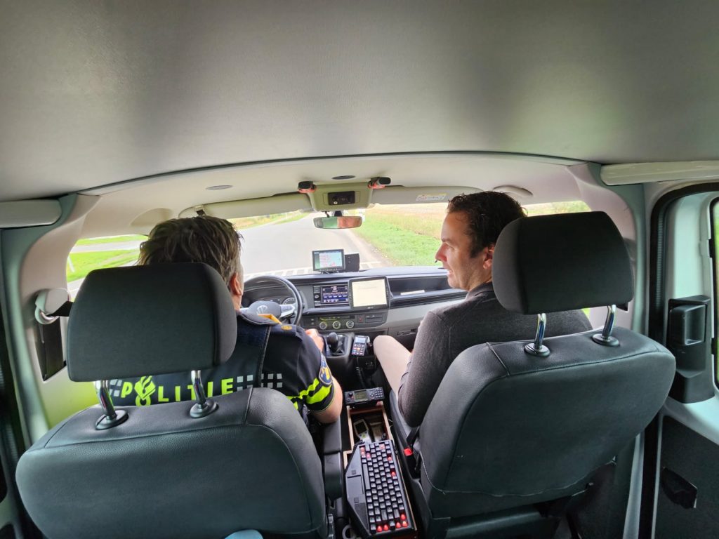 Bas Dirkmaat en Mark Versteeg zitten samen in de politiebus