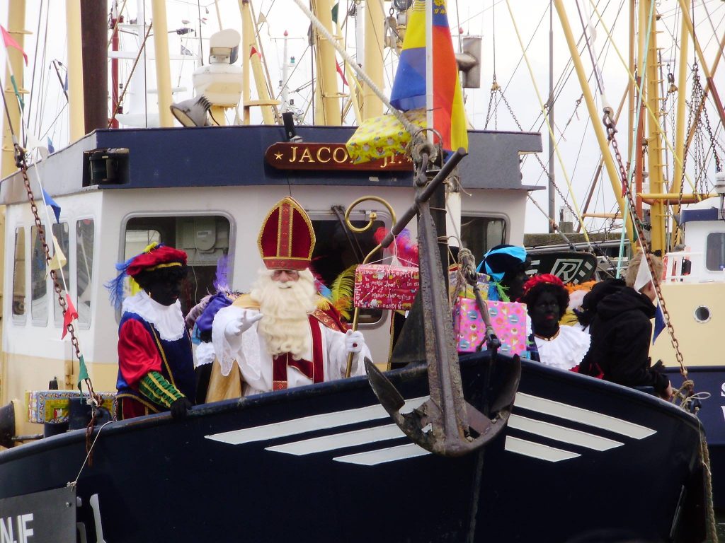 Sinterklaasintocht met de Sint en zijn pieten op de boot die zwaaien naar de kindjes