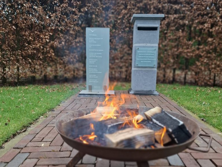 Symbolisch versturen van Hemelpost op de begraafplaats Wieringerwaard. Op de voorgrond een vuurkorf met erachter de hemelpostbrievenbus