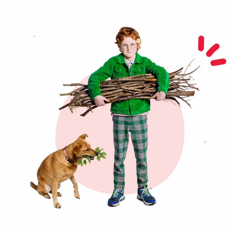 jongetje houdt een takkenbos vast. Er zit een hond naast.