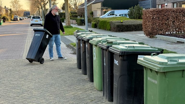 Prullenbakken aan de kant van de straat met een meneer links die een prullenbak neerzet