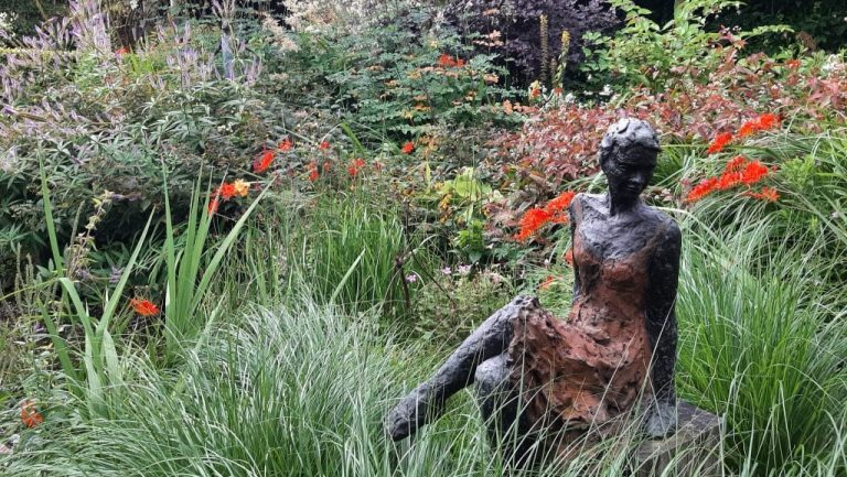 Nazomeren in Niedorp. Foto van een bronzen beeld van een vrouw in een tuin.