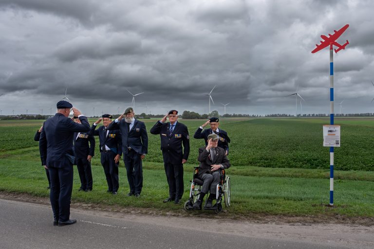Veteranen brengen een saluut bij de onthulling van een herdenkingspaal voor een vliegtuigcrash uit de Tweede Wereldoorlog aan de Westfriesedijk bij Lutjewinkel.