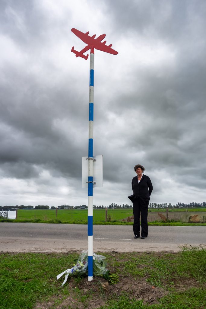 Burgemeester Rian van Dam bij herdenkingspaal voor een Duitse vliegtuigcrash uit de Tweede Wereldoorlog aan de Westfriesedijk bij Lutjewinkel.
